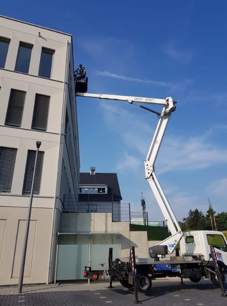 Fassadenreinigung an einem modernen Gebäude mithilfe einer Hebebühne