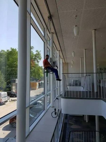 Reinigung einer hohen Innenverglasung mit Abseiltechnik in einem modernen Gebäude